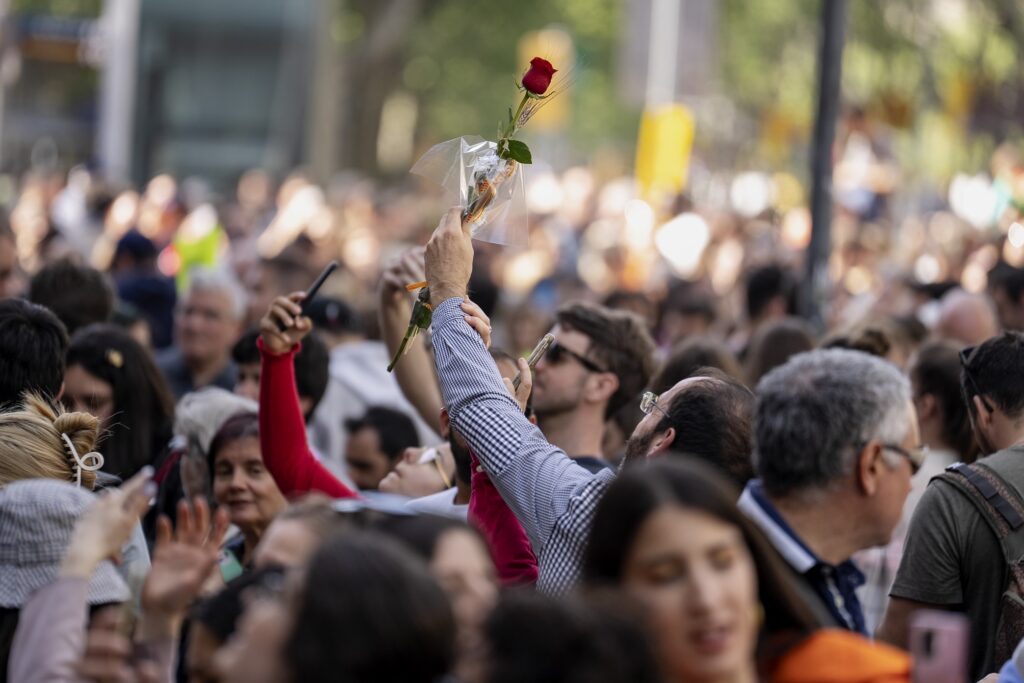 Un home aixeca una rosa emmig d'un grup de gent per Sant Jordi.
